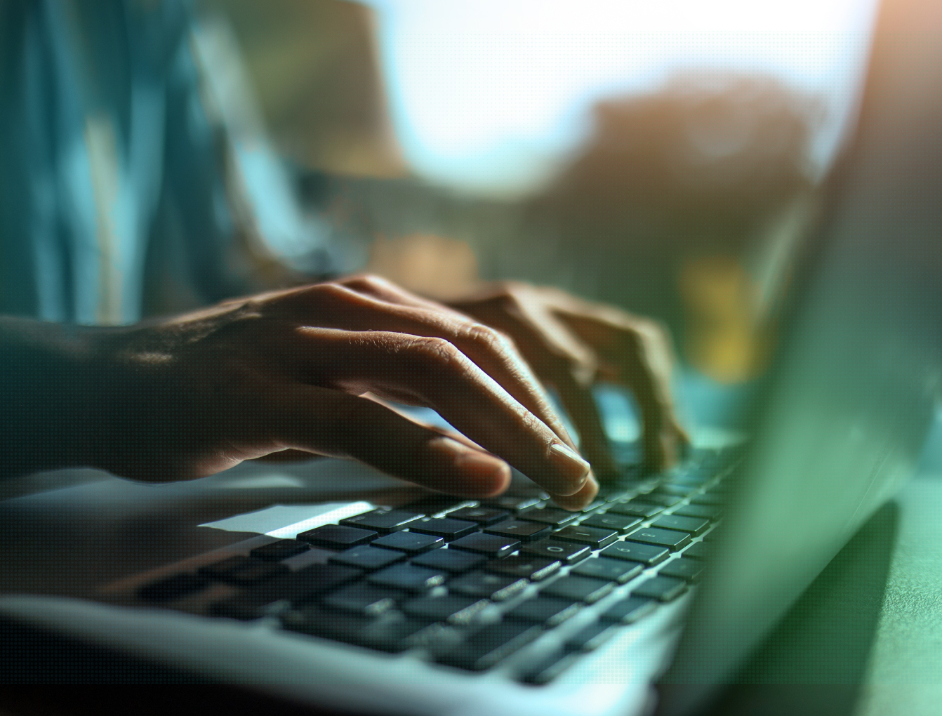 Close-up of hands typing on a laptop keyboard
